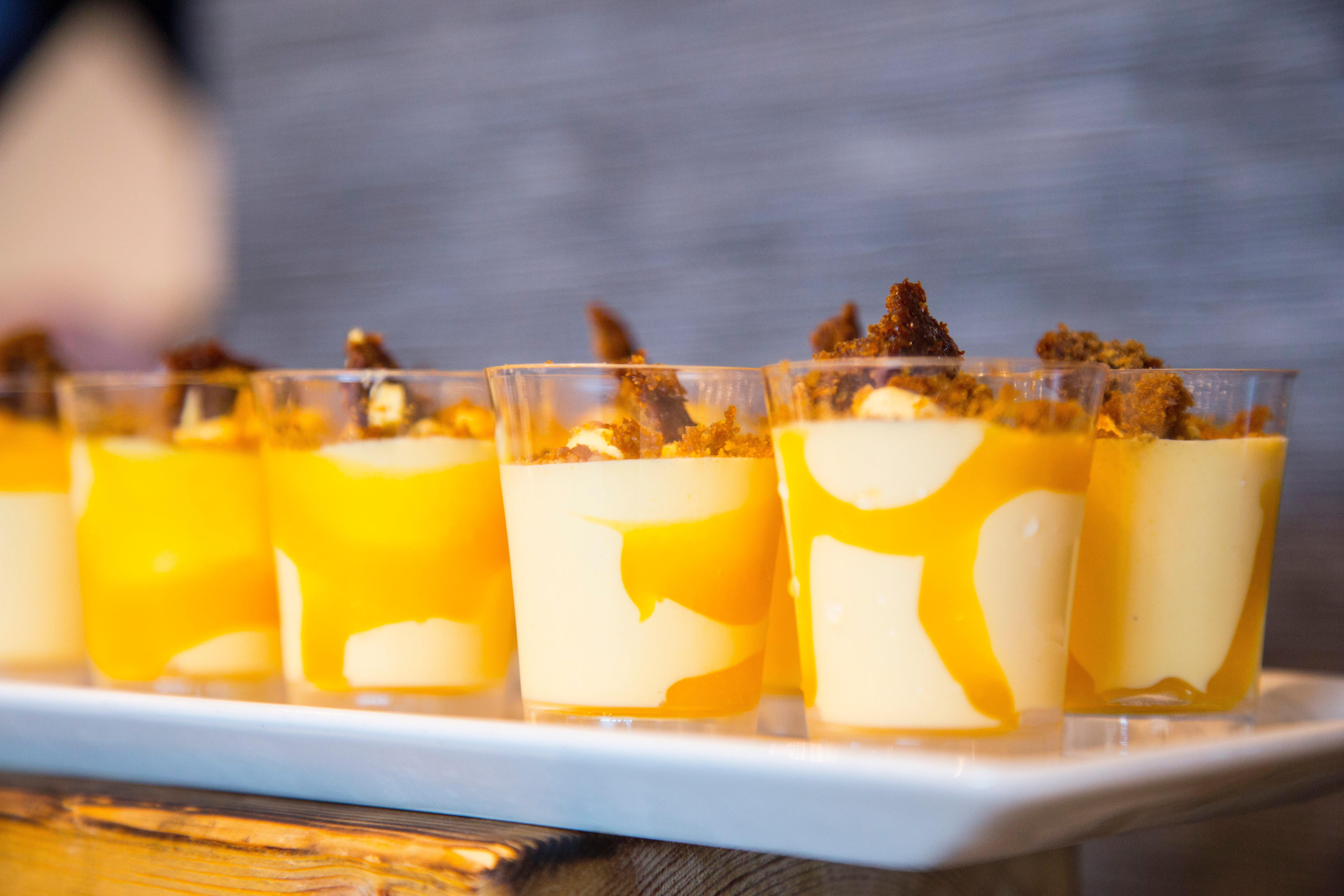 فندق فوكو سانت دايفيدز كارديف المظهر الخارجي الصورة The photo displays a series of dessert cups arranged on a white platter. Each cup contains a layered dessert with a creamy base, likely a custard or mousse, topped with a vibrant orange sauce that resembles mango or passion fruit. The cups are garnis
