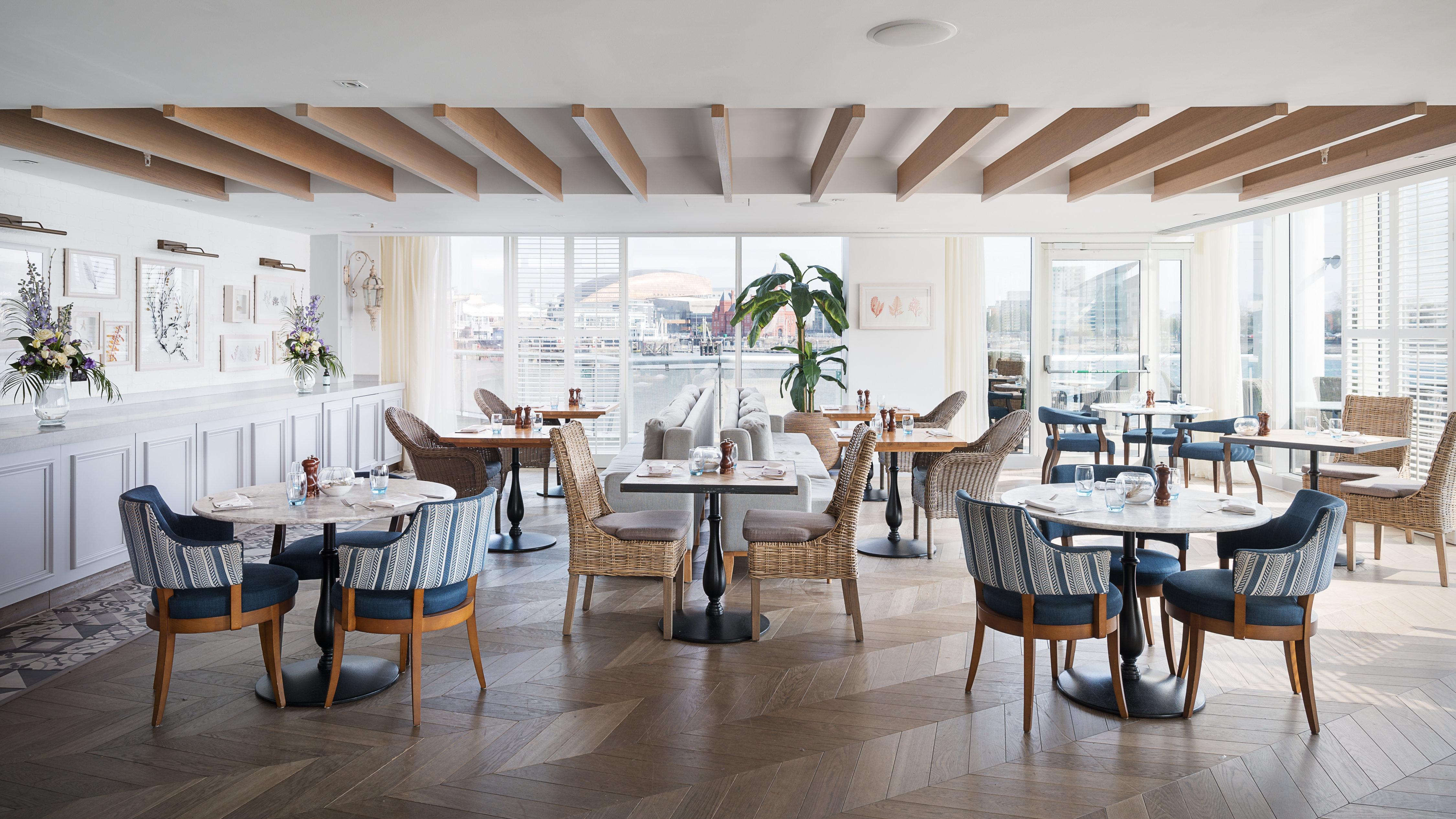 فندق فوكو سانت دايفيدز كارديف المظهر الخارجي الصورة The photo shows a stylish and modern restaurant interior. The space features several tables with comfortable chairs arranged thoughtfully. Large windows allow natural light to fill the room, providing a view of the outside. The decor includes neutral